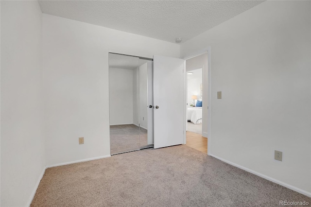 unfurnished bedroom with light colored carpet, a textured ceiling, and a closet