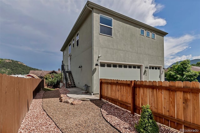 265 Upper Glenway, Palmer Lake, CO 80133 - view of side of property with a garage, stucco siding, and stairway
