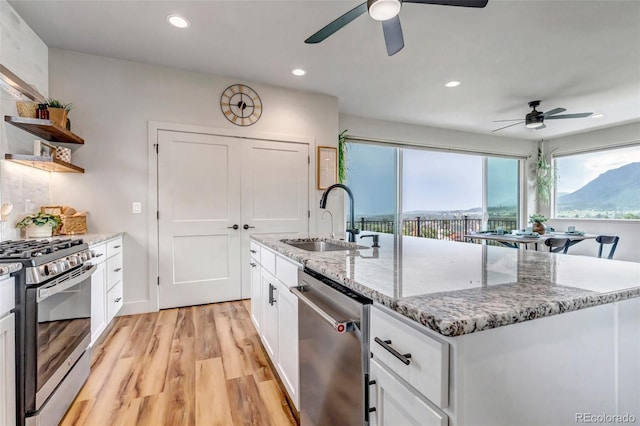 265 Upper Glenway, Palmer Lake, CO 80133 - kitchen with appliances with stainless steel finishes, a ceiling fan, open shelves, light wood-type flooring, and white cabinetry
