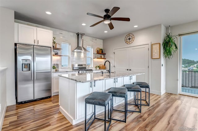 265 Upper Glenway, Palmer Lake, CO 80133 - kitchen featuring appliances with stainless steel finishes, wall chimney exhaust hood, open shelves, ceiling fan, and light wood finished floors
