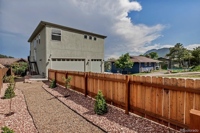 265 Upper Glenway, Palmer Lake, CO 80133 - back of property featuring a garage, stucco siding, a mountain view, and stairway