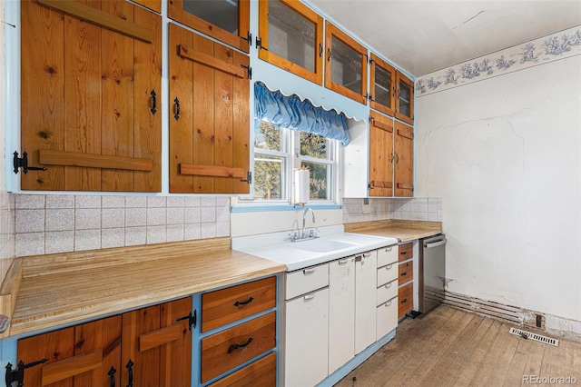 kitchen with dishwasher, white cabinets, sink, light hardwood / wood-style flooring, and decorative backsplash