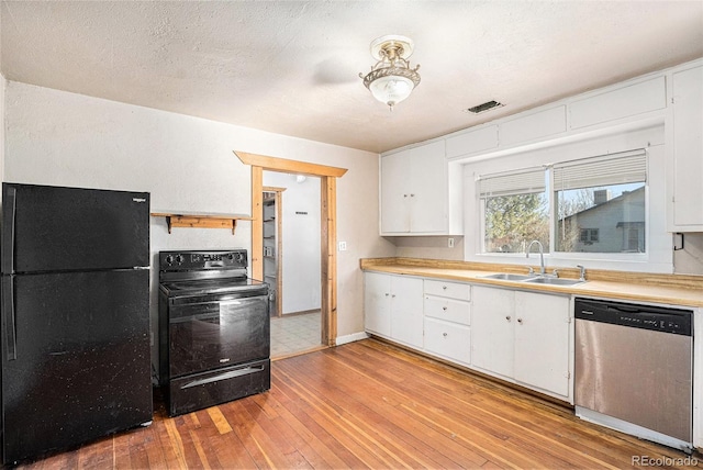 kitchen featuring light wood-type flooring, a textured ceiling, sink, black appliances, and white cabinetry