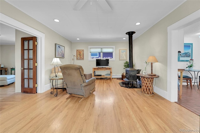 living room featuring baseboards, baseboard heating, wood finished floors, and a wood stove