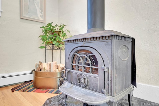 room details featuring a wood stove, wood finished floors, baseboard heating, and a textured wall