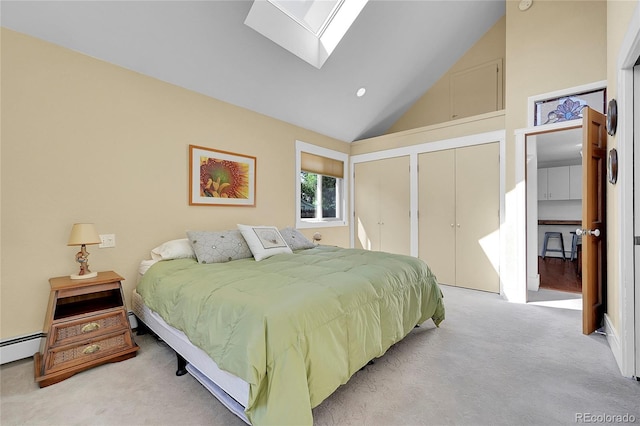 bedroom with lofted ceiling with skylight, light colored carpet, two closets, and a baseboard radiator