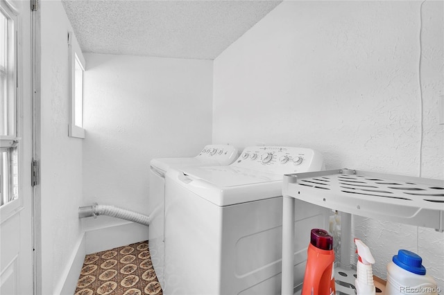 clothes washing area with separate washer and dryer, a textured ceiling, laundry area, and a textured wall