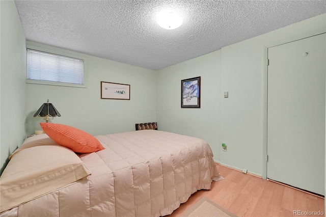 bedroom with light wood finished floors and a textured ceiling