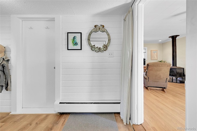 hallway featuring a textured ceiling, wood finished floors, and a baseboard radiator