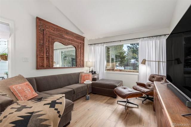 living area with light wood-style flooring and vaulted ceiling