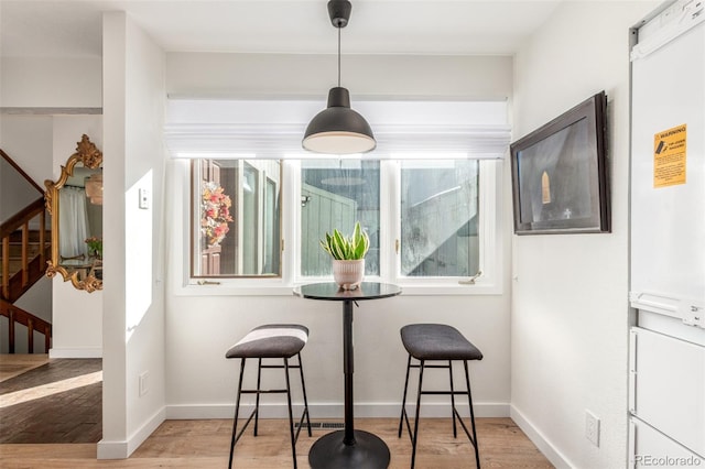 dining room featuring light wood finished floors, stairway, a wealth of natural light, and baseboards