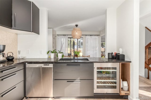 kitchen featuring dishwasher, beverage cooler, dark stone countertops, and a sink