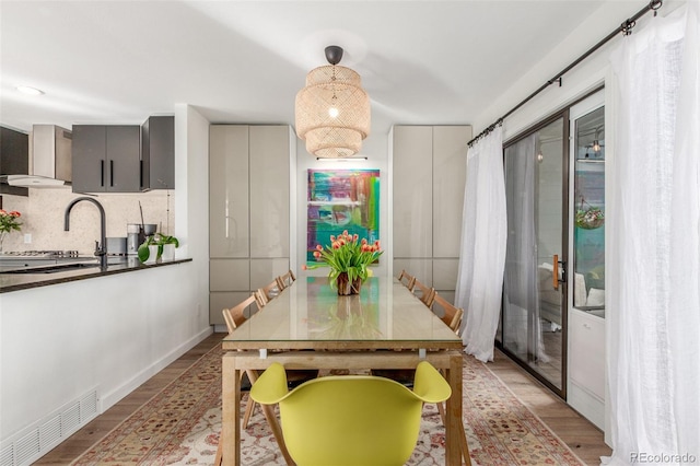 dining area featuring visible vents, light wood-style flooring, and baseboards