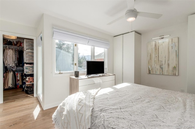 bedroom with baseboards, ceiling fan, a spacious closet, light wood-style floors, and a closet