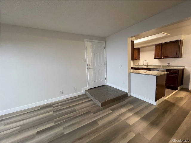 kitchen featuring dark wood-style floors, baseboards, light countertops, and a sink