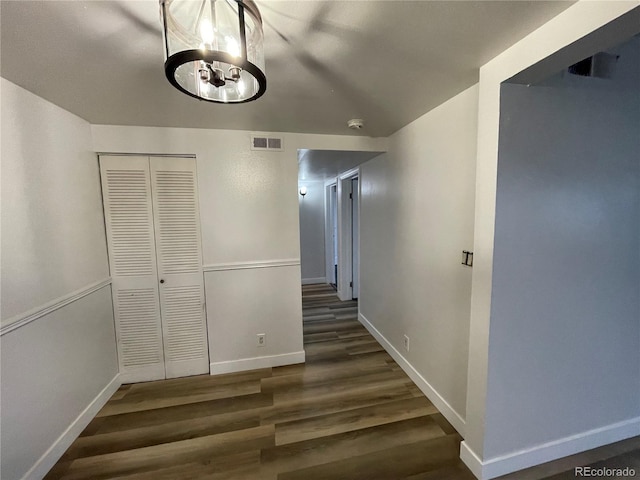 hall featuring a chandelier, visible vents, baseboards, and wood finished floors