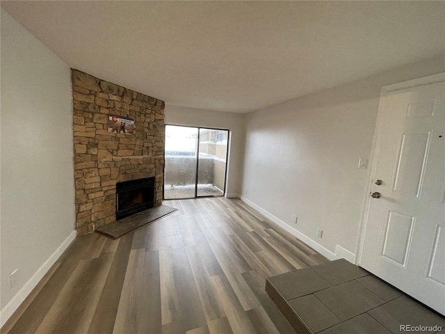 unfurnished living room with a fireplace, baseboards, and wood finished floors