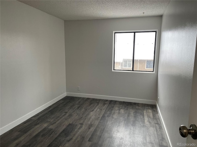 unfurnished room with baseboards, dark wood finished floors, and a textured ceiling