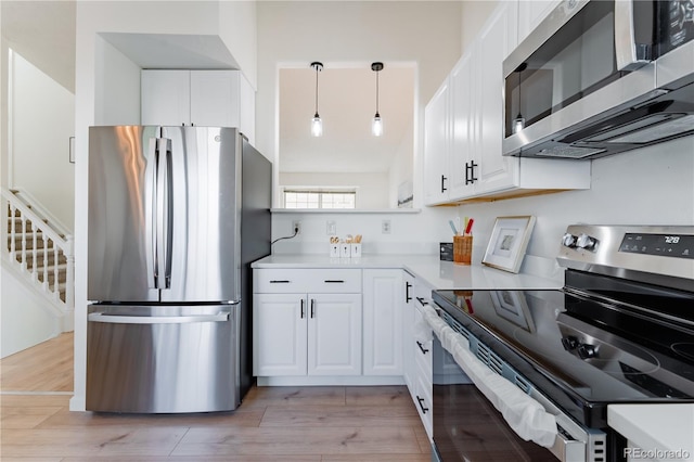 4249 S Biscay Cir, Aurora, CO 80013 - kitchen featuring appliances with stainless steel finishes, white cabinets, light countertops, light wood finished floors, and decorative light fixtures