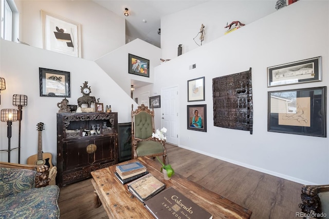 living room with a towering ceiling and dark hardwood / wood-style flooring