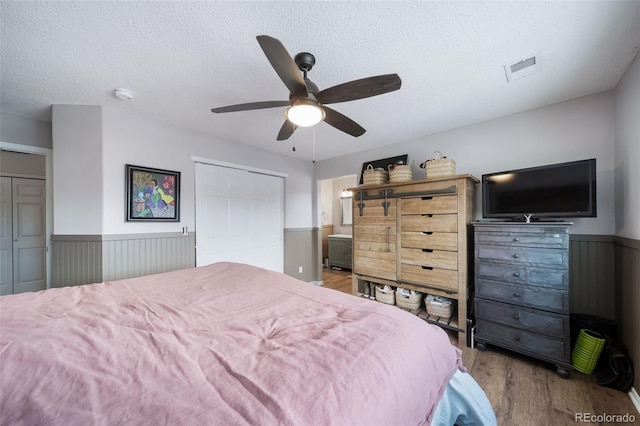 bedroom featuring light hardwood / wood-style floors, a textured ceiling, a closet, and ceiling fan