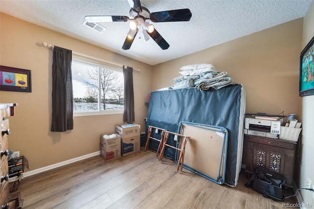 bedroom with a textured ceiling, light hardwood / wood-style flooring, and ceiling fan