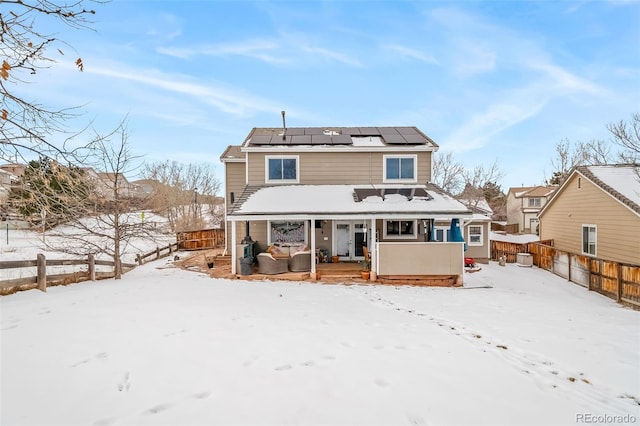 snow covered property with covered porch and solar panels