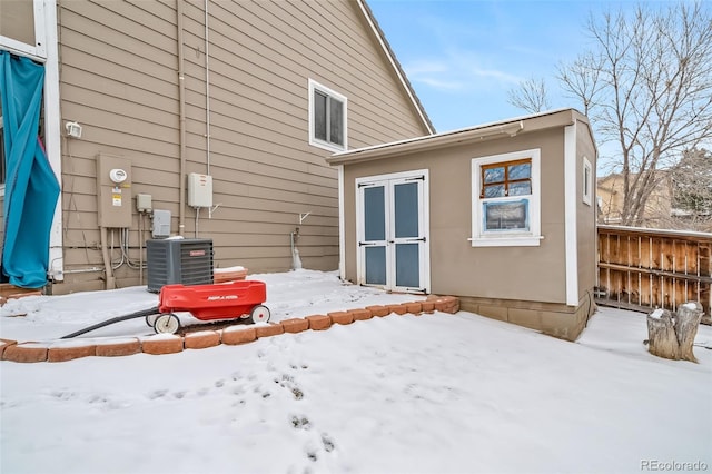 snow covered house featuring central AC unit