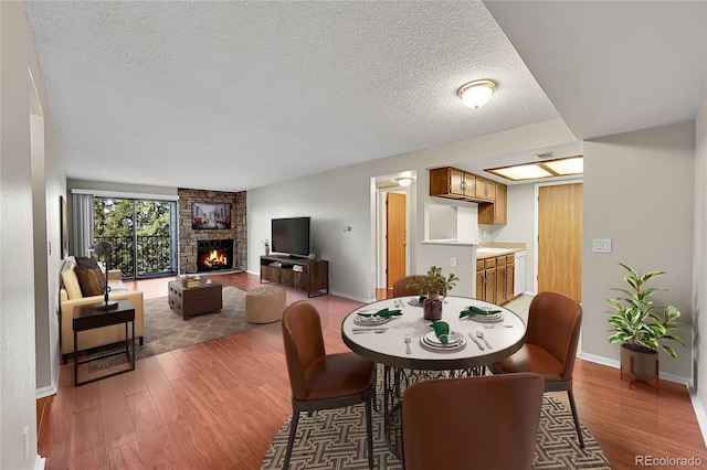 dining area with a textured ceiling, wood-type flooring, and a fireplace