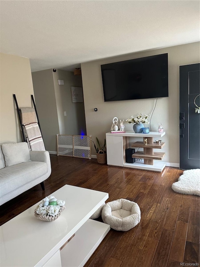 living room with a textured ceiling, baseboards, and hardwood / wood-style flooring