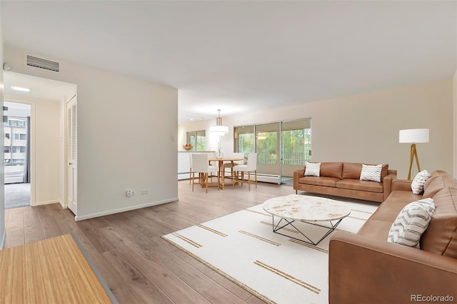 living room with baseboards, visible vents, and wood finished floors