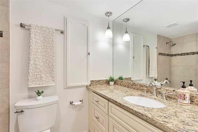 full bathroom with toilet, visible vents, a tile shower, and vanity