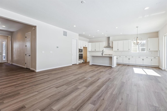 unfurnished living room featuring sink, a chandelier, and light hardwood / wood-style flooring