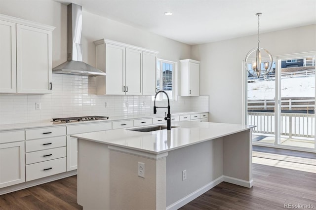 kitchen featuring stainless steel gas cooktop, sink, white cabinets, and wall chimney exhaust hood