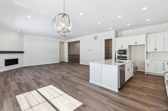 kitchen featuring built in microwave, sink, a center island with sink, and white cabinets