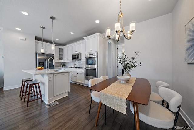 kitchen featuring tasteful backsplash, visible vents, appliances with stainless steel finishes, an inviting chandelier, and a sink