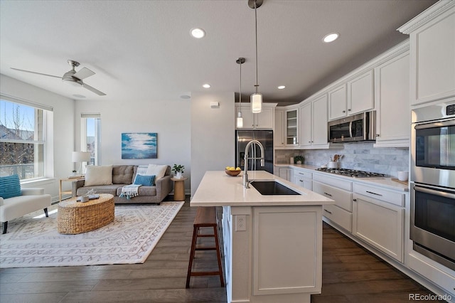 kitchen featuring tasteful backsplash, dark wood-type flooring, open floor plan, stainless steel appliances, and a sink