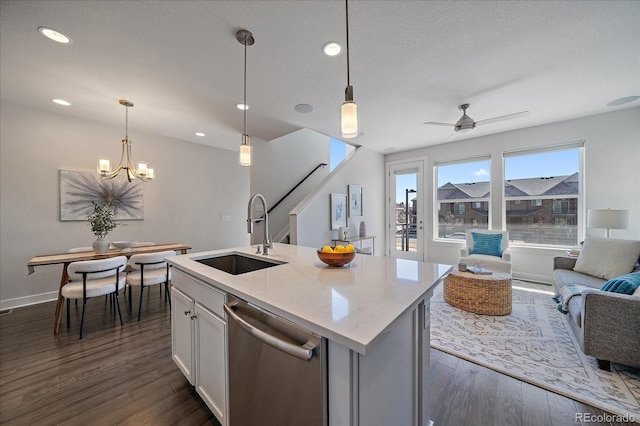 kitchen with a sink, decorative light fixtures, stainless steel dishwasher, open floor plan, and dark wood finished floors