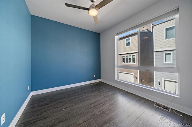 unfurnished room featuring visible vents, baseboards, dark wood-type flooring, and a ceiling fan