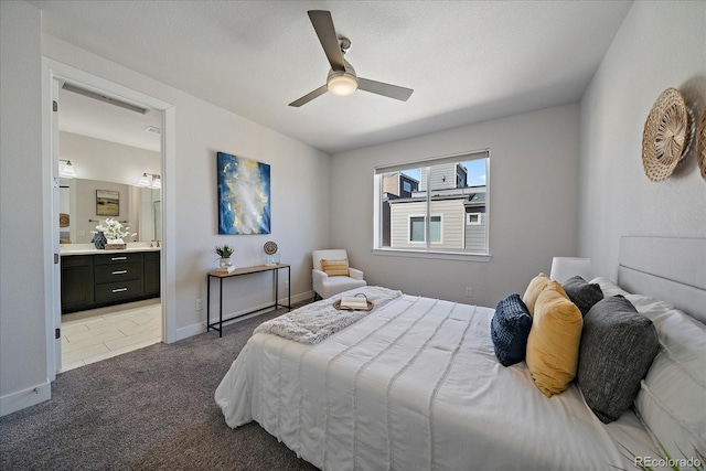 bedroom with baseboards, ensuite bathroom, carpet, and a ceiling fan