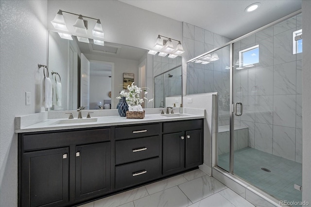 full bathroom featuring a sink, marble finish floor, a stall shower, and double vanity