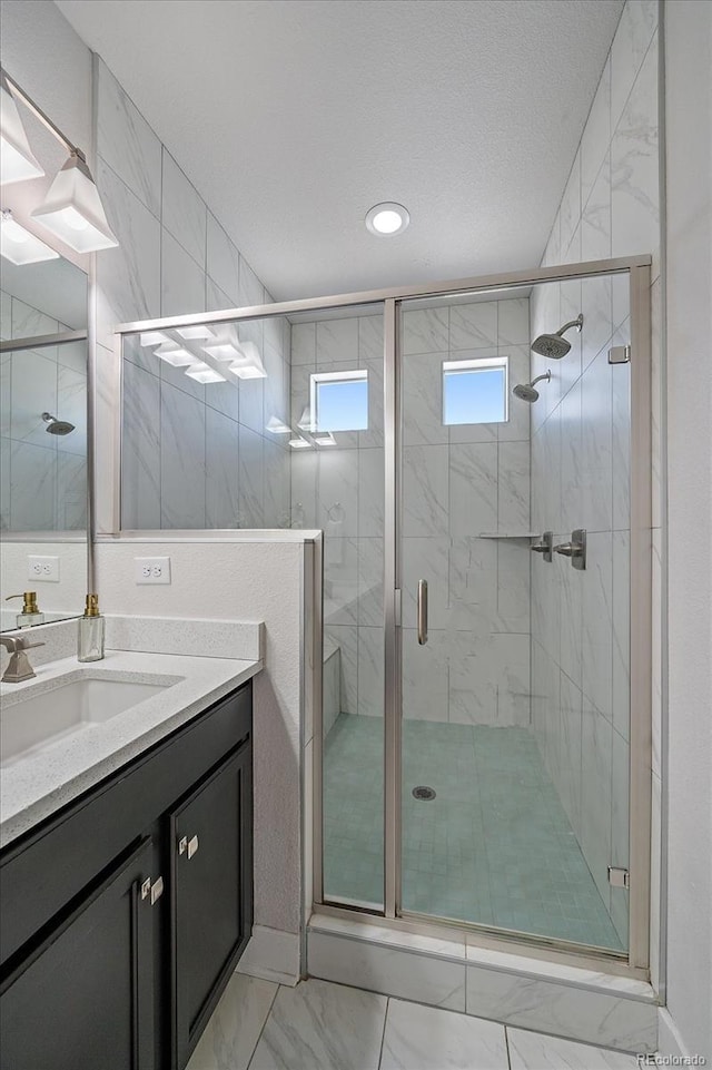 full bathroom featuring a textured ceiling, marble finish floor, a stall shower, and vanity