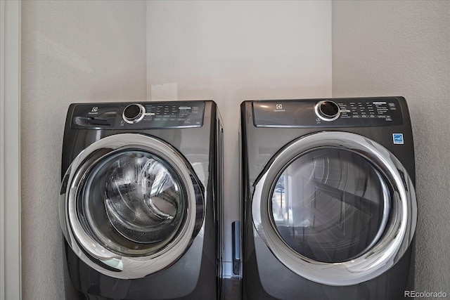 laundry area with laundry area, washer and dryer, and a textured wall