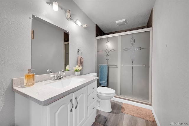 bathroom with an enclosed shower, vanity, wood-type flooring, and a textured ceiling