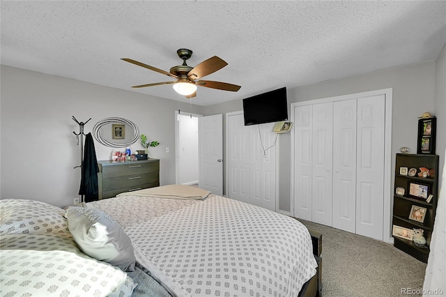 carpeted bedroom featuring ceiling fan, a textured ceiling, and two closets