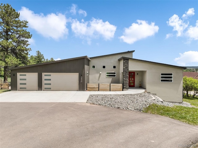 3630 Mesa Verde Rd, Monument, CO 80132 - modern home featuring a garage, concrete driveway, stucco siding, and stone siding