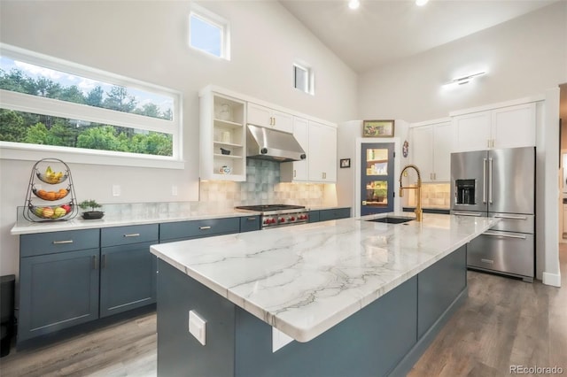 3630 Mesa Verde Rd, Monument, CO 80132 - kitchen with stainless steel appliances, under cabinet range hood, a towering ceiling, decorative backsplash, and wood finished floors