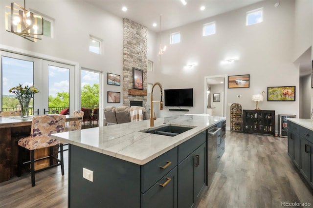 3630 Mesa Verde Rd, Monument, CO 80132 - kitchen featuring a high ceiling, a fireplace, wood finished floors, stainless steel dishwasher, and a kitchen island with sink