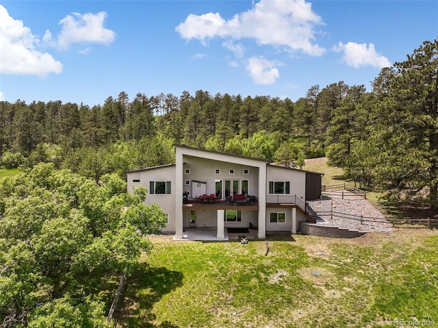 3630 Mesa Verde Rd, Monument, CO 80132 - back of property with a wooded view, stucco siding, a yard, a deck, and a patio