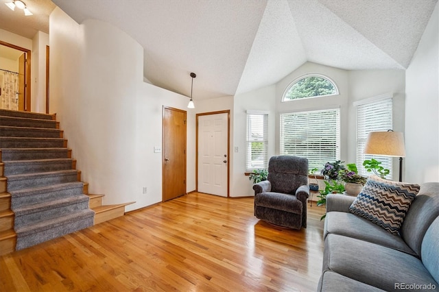 5513 S Yank Ct, Littleton, CO 80127 - living room with light wood-style flooring, vaulted ceiling, stairs, and a textured ceiling